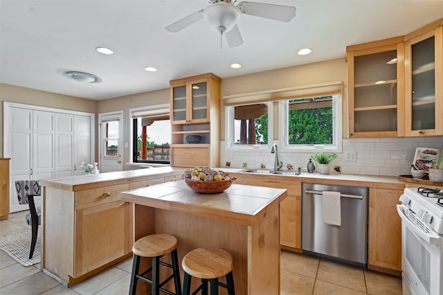 3046 Plaza Blanca, Santa Fe, NM 87507 - kitchen featuring stainless steel dishwasher, a center island, a breakfast bar, white range with gas cooktop, and tile countertops