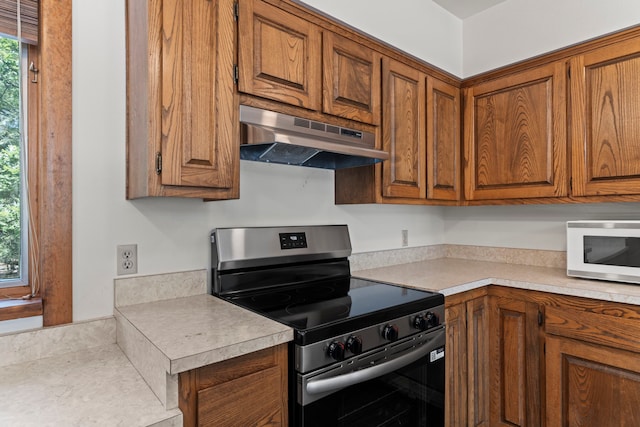 320 Valle Del Sol, White Rock, NM 87547 - kitchen with stainless steel range with electric stovetop, under cabinet range hood, white microwave, and brown cabinetry