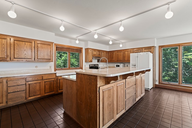 320 Valle Del Sol, White Rock, NM 87547 - kitchen featuring white refrigerator with ice dispenser, track lighting, dark tile patterned floors, and brown cabinetry