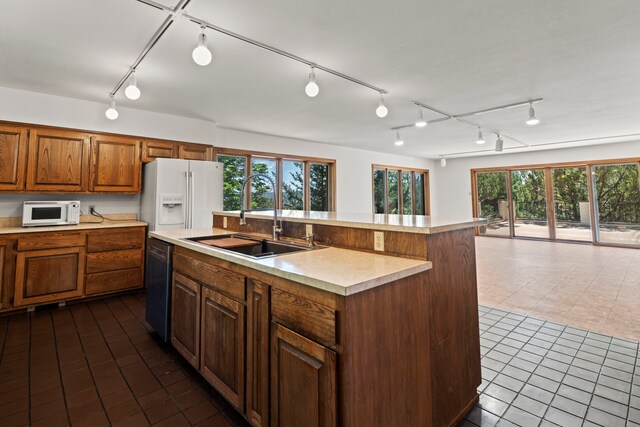 320 Valle Del Sol, White Rock, NM 87547 - kitchen with white appliances, light countertops, dark tile patterned flooring, a kitchen island with sink, and rail lighting