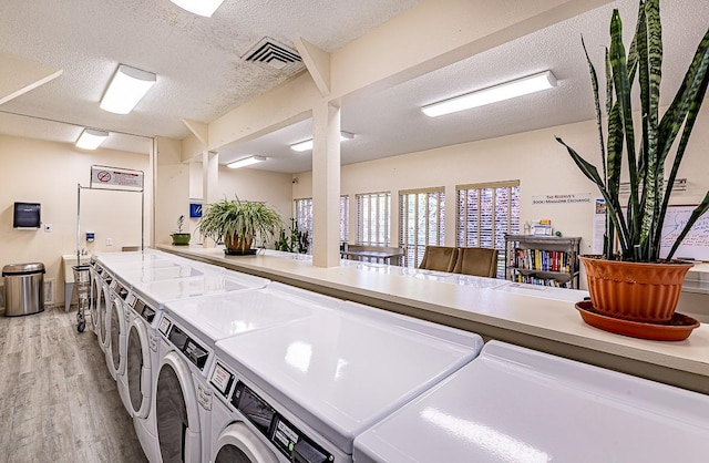 941 Calle Mejia Unit 413, Santa Fe, NM 87501 - communal laundry room featuring washer and clothes dryer, light wood-style floors, and a textured ceiling