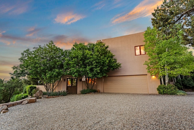 19 Camino Don Carlos, Santa Fe, NM 87506 - view of front of home with gravel driveway, stucco siding, and an attached garage