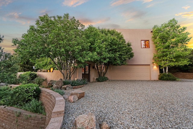 19 Camino Don Carlos, Santa Fe, NM 87506 - pueblo-style house featuring stucco siding, an attached garage, and driveway