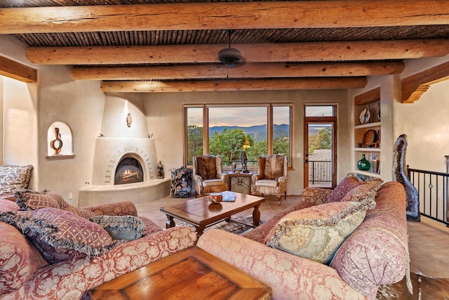 19 Camino Don Carlos, Santa Fe, NM 87506 - living room with a wood ceiling with exposed beams, tile patterned flooring, a lit fireplace, a mountain view, and built in shelves