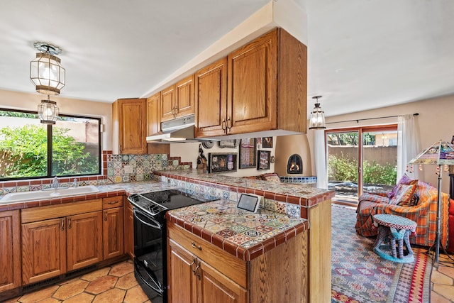 234 Ambrosio Unit A, Santa Fe, NM 87501 - kitchen with electric range, under cabinet range hood, a peninsula, brown cabinetry, and tasteful backsplash