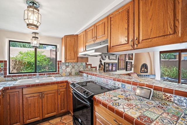 234 Ambrosio Unit A, Santa Fe, NM 87501 - kitchen with black range with electric stovetop, under cabinet range hood, healthy amount of natural light, and brown cabinets