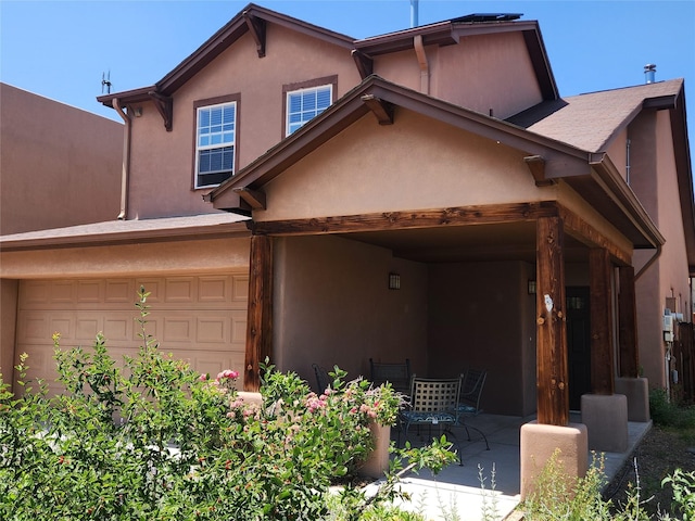 310 Grand Cyn, White Rock, NM 87547 - view of front of house featuring stucco siding, a patio, and a garage