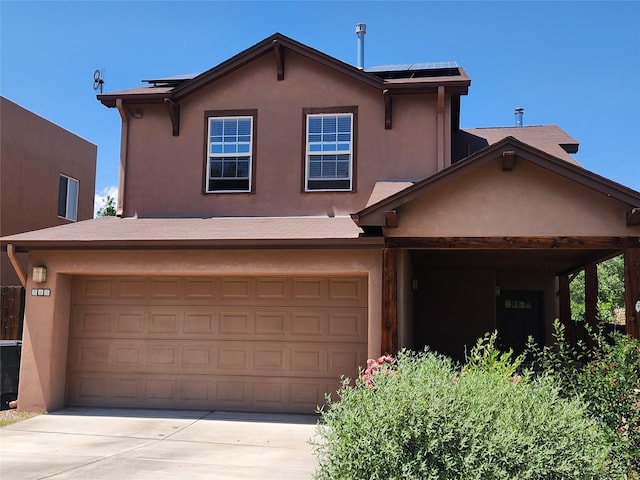 310 Grand Cyn, White Rock, NM 87547 - view of front of home featuring stucco siding, solar panels, driveway, and an attached garage