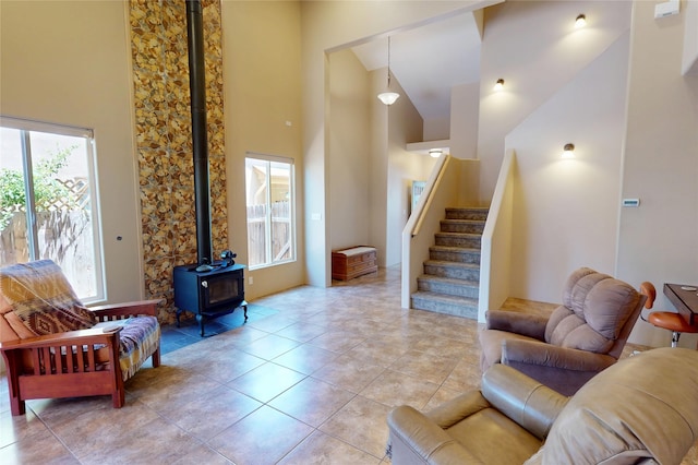 310 Grand Cyn, White Rock, NM 87547 - living area with healthy amount of natural light, a wood stove, a towering ceiling, stairway, and light tile patterned floors