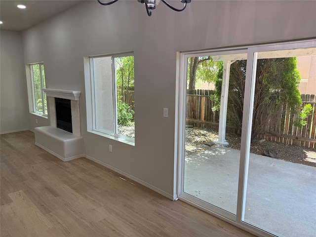 7512 Sagebrush, Santa Fe, NM 87507 - unfurnished living room featuring wood finished floors, healthy amount of natural light, a fireplace with raised hearth, recessed lighting, and a high ceiling