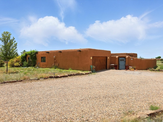 62 Camerada Loop, Santa Fe, NM 87508 - rear view of house with gravel driveway and a garage