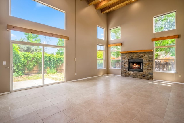 4485 Dancing Ground Rd, Santa Fe, NM 87507 - unfurnished living room with light tile patterned floors, a towering ceiling, a wood ceiling with exposed beams, and a stone fireplace