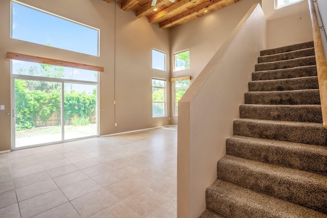 4485 Dancing Ground Rd, Santa Fe, NM 87507 - stairs with a wood ceiling with exposed beams, tile patterned floors, and a towering ceiling