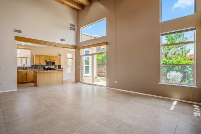 4485 Dancing Ground Rd, Santa Fe, NM 87507 - unfurnished living room with a towering ceiling, beam ceiling, light tile patterned floors, and healthy amount of natural light