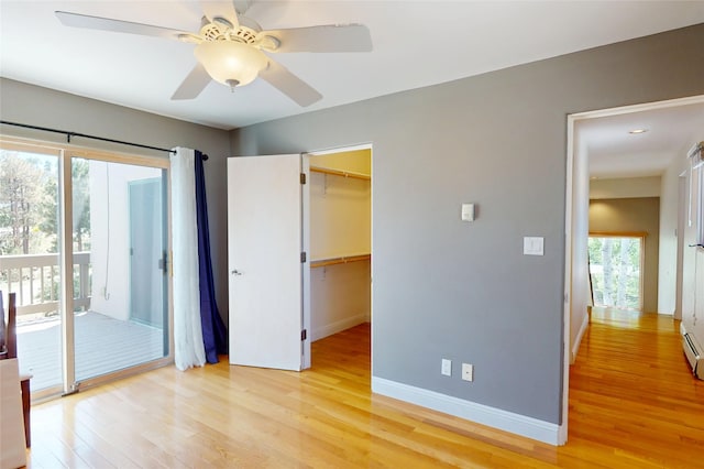 5045 Carriage House Dr, Los Alamos, NM 87544 - unfurnished bedroom featuring light wood-style floors, access to exterior, a walk in closet, a ceiling fan, and a baseboard heating unit