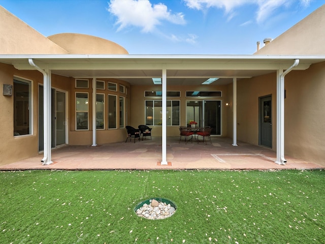 16 Coyote Pass Rd, Santa Fe, NM 87508 - back of property with stucco siding, a lawn, and a patio area