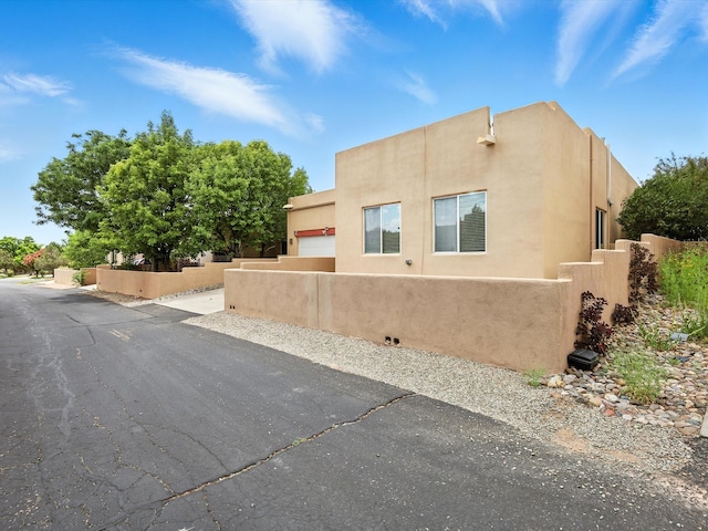 16 Coyote Pass Rd, Santa Fe, NM 87508 - view of side of home with an attached garage, stucco siding, and driveway
