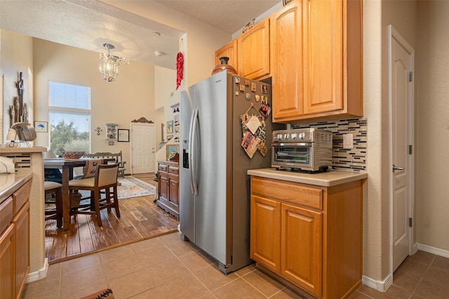 4351 San Benito Unit A, Santa Fe, NM 87507 - kitchen with stainless steel refrigerator with ice dispenser, light tile patterned flooring, light countertops, a chandelier, and backsplash