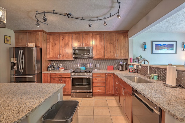 7513 Kachina Loop, Santa Fe, NM 87507 - kitchen featuring appliances with stainless steel finishes, brown cabinets, a textured ceiling, tasteful backsplash, and light stone countertops