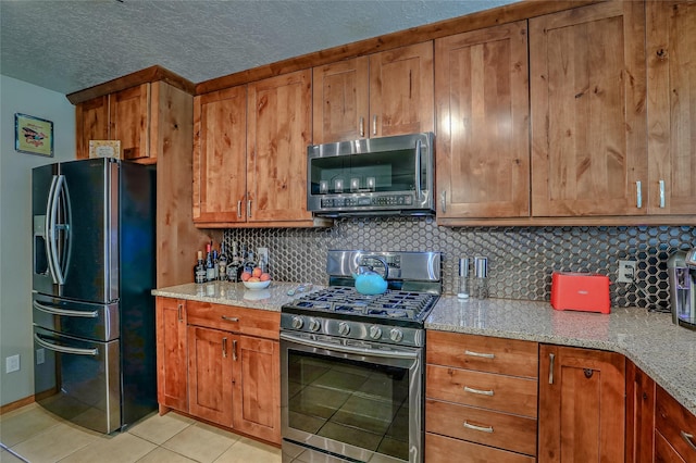 7513 Kachina Loop, Santa Fe, NM 87507 - kitchen with appliances with stainless steel finishes, brown cabinetry, backsplash, light stone counters, and a textured ceiling