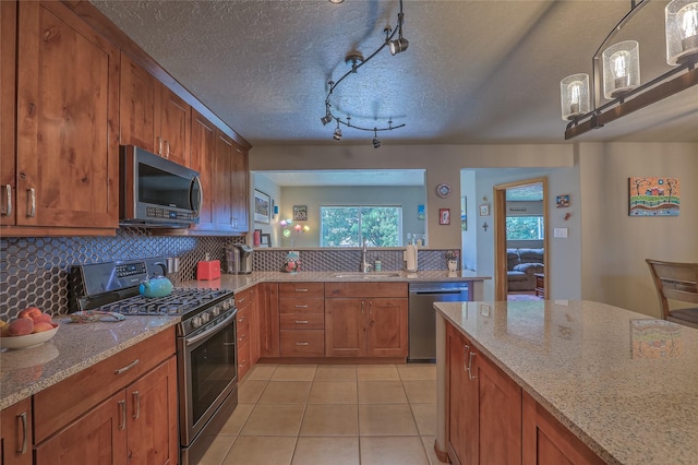 7513 Kachina Loop, Santa Fe, NM 87507 - kitchen with appliances with stainless steel finishes, brown cabinetry, tasteful backsplash, light stone counters, and a textured ceiling