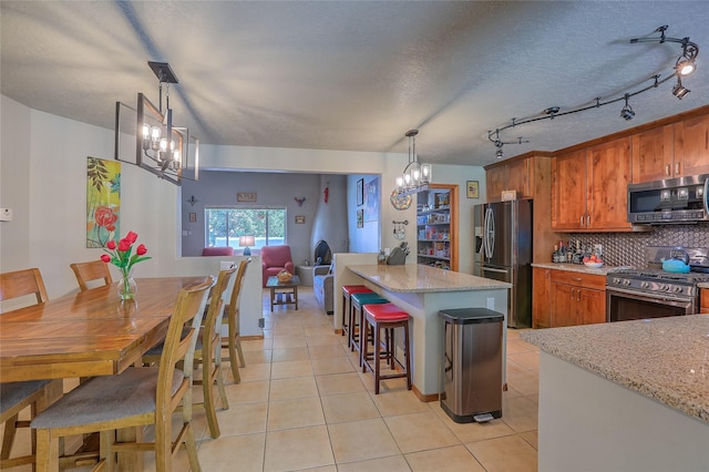 7513 Kachina Loop, Santa Fe, NM 87507 - kitchen featuring appliances with stainless steel finishes, a chandelier, tasteful backsplash, brown cabinets, and light tile patterned floors