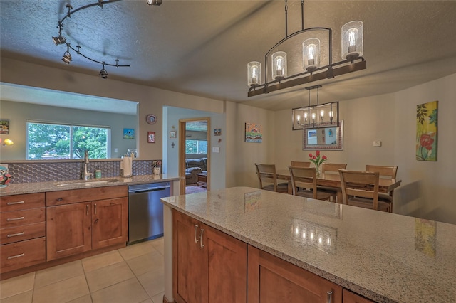 7513 Kachina Loop, Santa Fe, NM 87507 - kitchen with stainless steel dishwasher, brown cabinetry, light tile patterned flooring, light stone counters, and a textured ceiling
