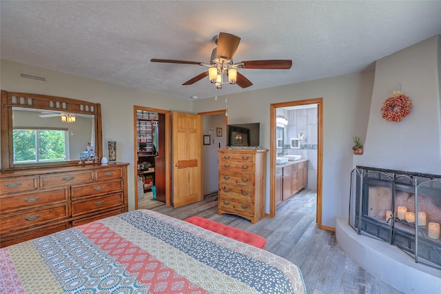 7513 Kachina Loop, Santa Fe, NM 87507 - bedroom with light wood-style flooring, a textured ceiling, ceiling fan, and ensuite bath