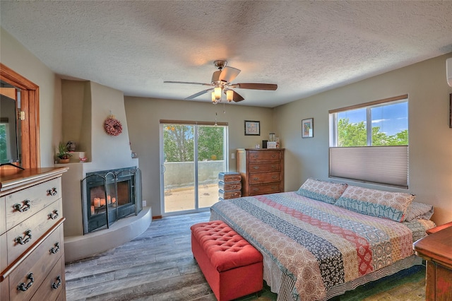 7513 Kachina Loop, Santa Fe, NM 87507 - bedroom with access to outside, wood finished floors, a multi sided fireplace, a textured ceiling, and ceiling fan