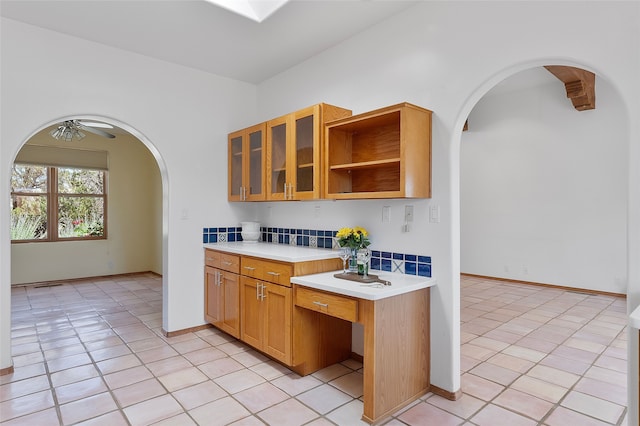 8 Antigua Ct, Santa Fe, NM 87508 - kitchen with arched walkways, light countertops, light tile patterned floors, glass insert cabinets, and decorative backsplash