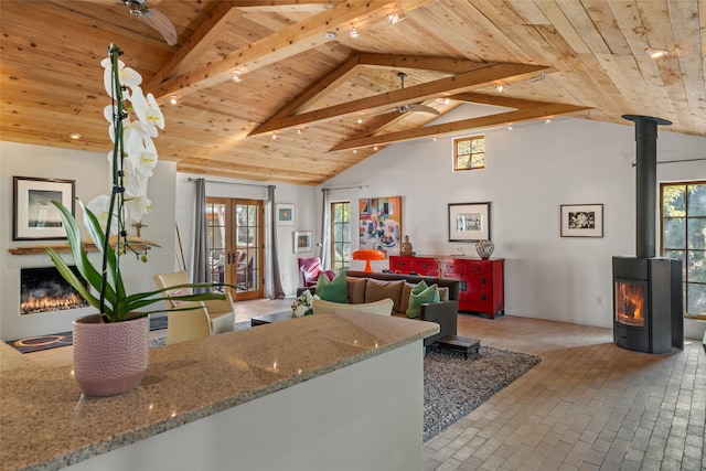 10 Sabina Ln, Santa Fe, NM 87508 - living area featuring a wooden ceiling with exposed beams, a wood stove, healthy amount of natural light, brick patterned floors, and high vaulted ceiling