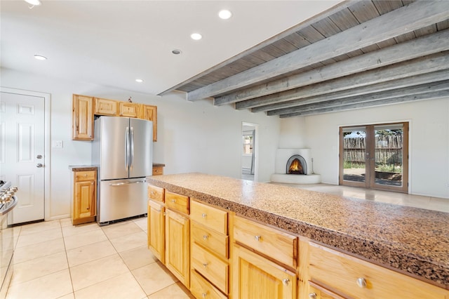 79 Moya Rd, Santa Fe, NM 87508 - kitchen featuring freestanding refrigerator, light tile patterned flooring, beam ceiling, a large fireplace, and light brown cabinetry