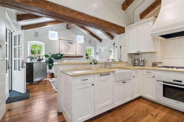 605 Acequia Madre, Santa Fe, NM 87505 - kitchen featuring white appliances, custom exhaust hood, a peninsula, decorative backsplash, and white cabinets