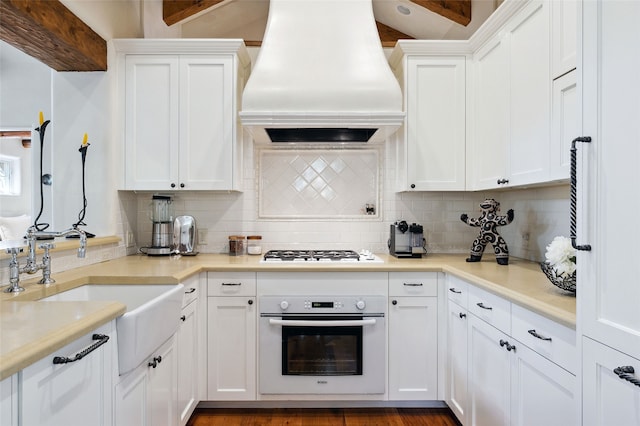 605 Acequia Madre, Santa Fe, NM 87505 - kitchen featuring white appliances, custom range hood, tasteful backsplash, white cabinetry, and beamed ceiling