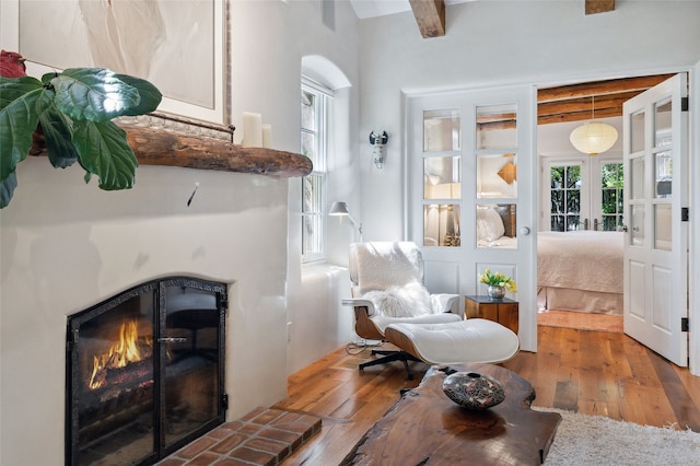605 Acequia Madre, Santa Fe, NM 87505 - sitting room featuring a fireplace, beam ceiling, wood-type flooring, and french doors
