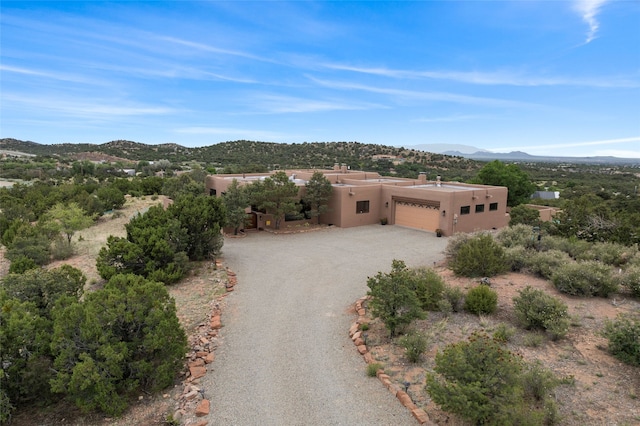 17 Sueno De Santa Fe, Santa Fe, NM 87505 - adobe home featuring a mountain view, stucco siding, a chimney, a garage, and gravel driveway