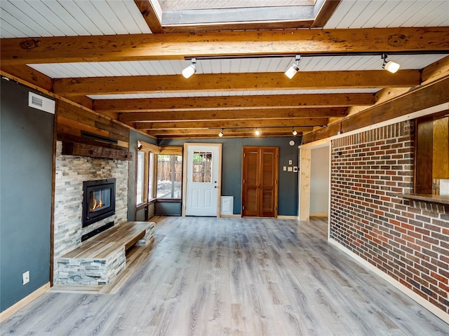 85 Chiquita Dr, White Rock, NM 87547 - unfurnished living room with light wood-style flooring, a stone fireplace, beamed ceiling, track lighting, and brick wall