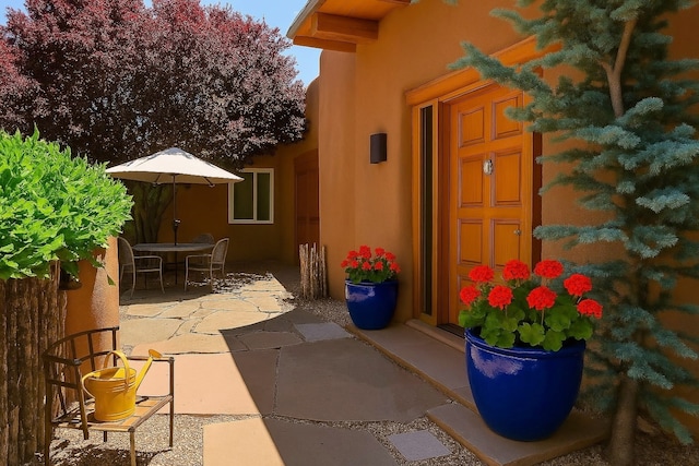 44 Lodge Cir Unit C, Santa Fe, NM 87506 - doorway to property featuring stucco siding, a patio, and outdoor dining area