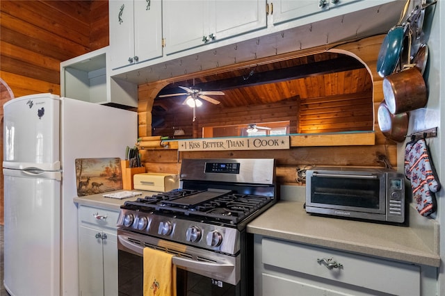 19 Canoe Ct, Jemez Springs, NM 87025 - kitchen featuring stainless steel range with gas cooktop, freestanding refrigerator, wooden walls, light countertops, and ceiling fan