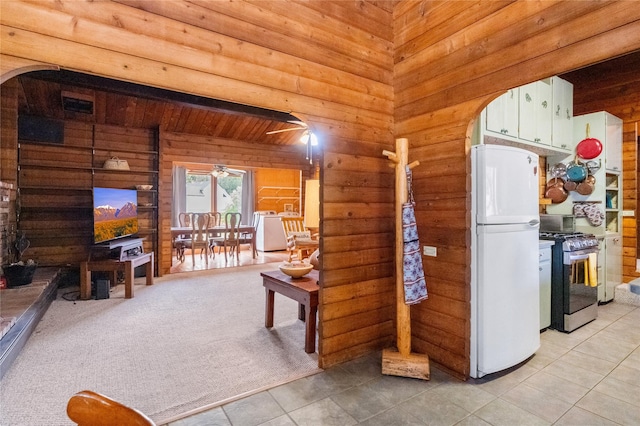 19 Canoe Ct, Jemez Springs, NM 87025 - kitchen with stainless steel gas range, freestanding refrigerator, arched walkways, light tile patterned floors, and wooden walls