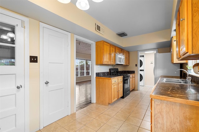 2122 41st Unit B, Los Alamos, NM 87544 - kitchen featuring black gas range, stacked washer and clothes dryer, white microwave, and dark countertops