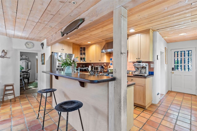 3B Camino Miguel, Santa Fe, NM 87506 - kitchen featuring wall chimney range hood, dark countertops, wooden ceiling, a kitchen breakfast bar, and tasteful backsplash