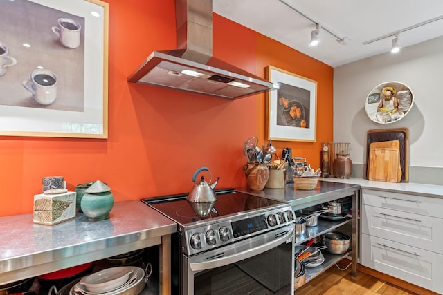 359 Garcia St, Santa Fe, NM 87501 - kitchen featuring wall chimney exhaust hood, stainless steel range with electric cooktop, track lighting, wood finished floors, and stainless steel counters