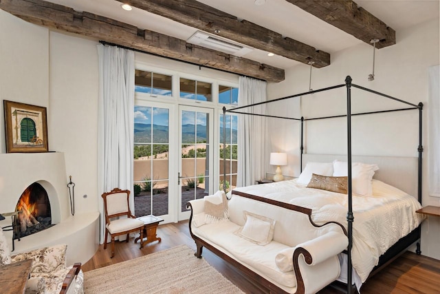 102 San Rafael Dr, Santa Fe, NM 87506 - bedroom featuring access to exterior, beam ceiling, wood finished floors, and a warm lit fireplace