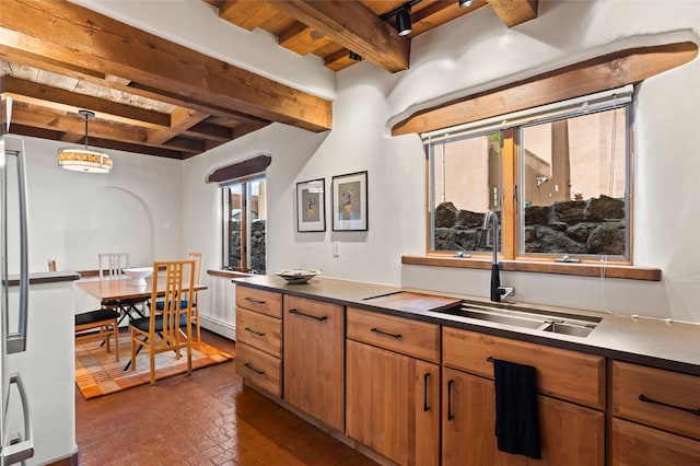 134 W Houghton St Unit D, Santa Fe, NM 87505 - kitchen featuring brick flooring, beamed ceiling, brown cabinets, pendant lighting, and dark countertops