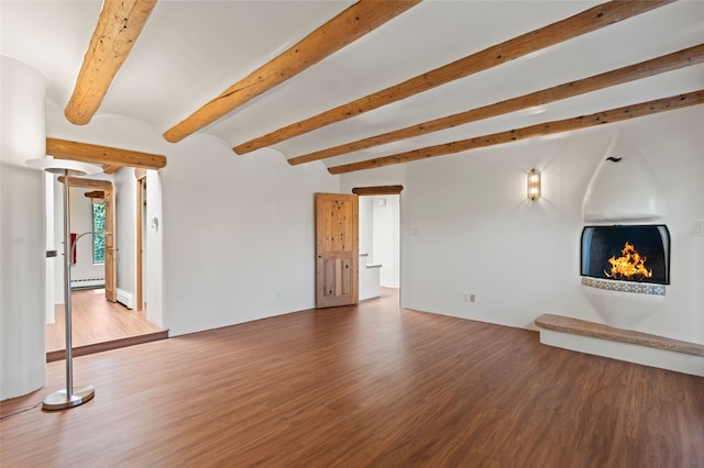 134 W Houghton St Unit D, Santa Fe, NM 87505 - unfurnished living room featuring a warm lit fireplace, wood finished floors, a baseboard radiator, and beam ceiling
