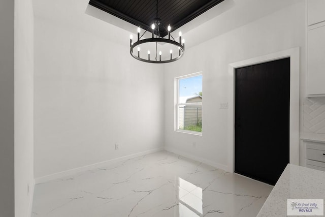 6245 Tiger Dr, Brownsville, TX 78521 - unfurnished dining area with light marble finish flooring, a raised ceiling, a chandelier, and baseboards