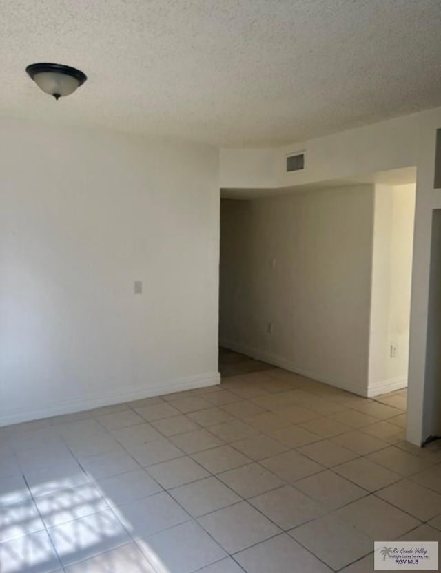 spare room with visible vents, a textured ceiling, and baseboards