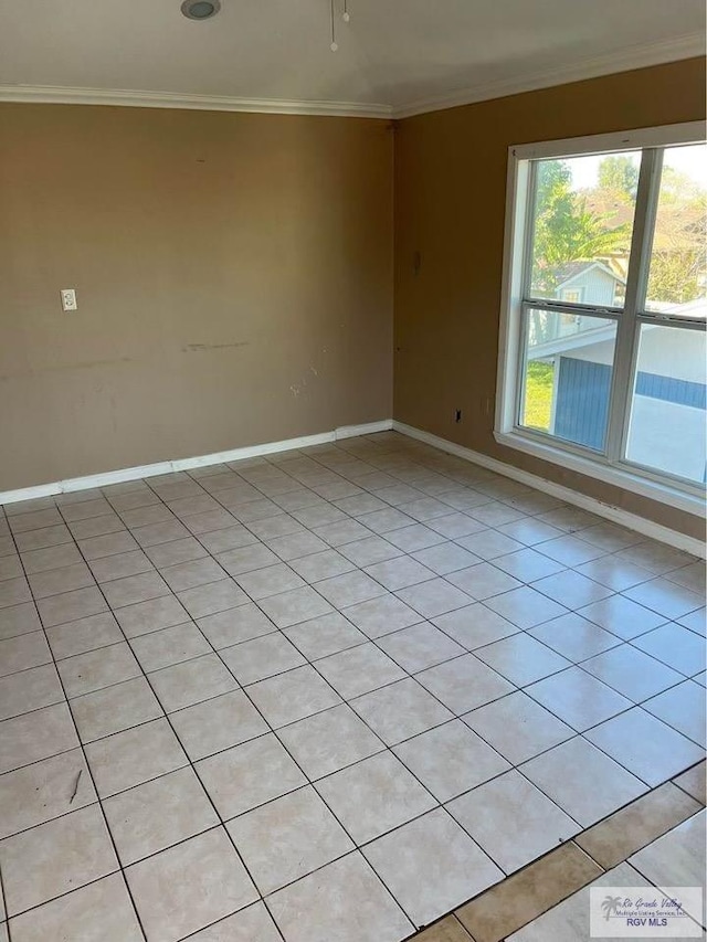 spare room with light tile patterned floors, baseboards, and ornamental molding