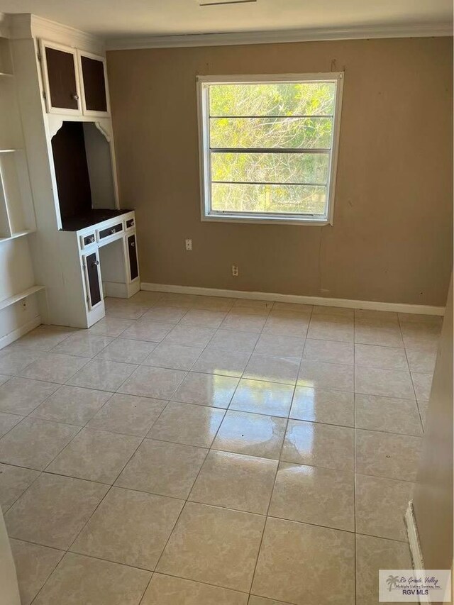 unfurnished living room featuring light tile patterned floors, baseboards, and ornamental molding